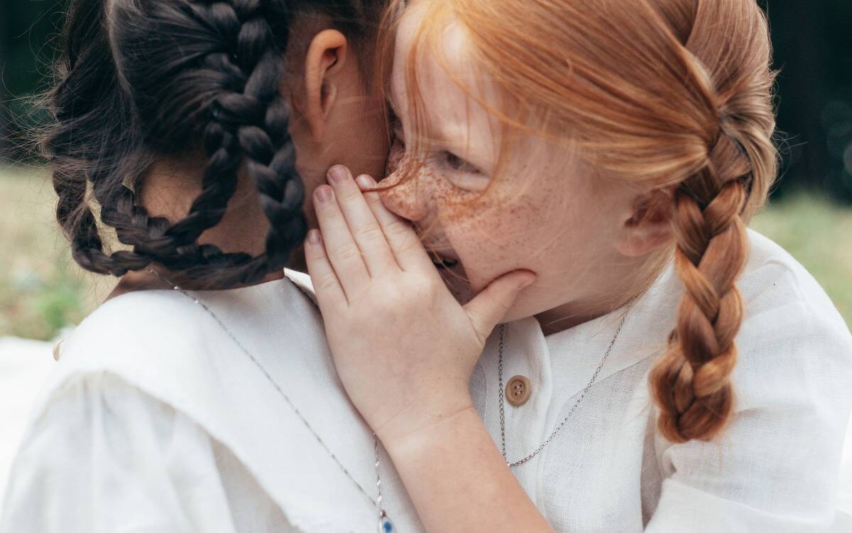A little girl telling her friend a secret.
