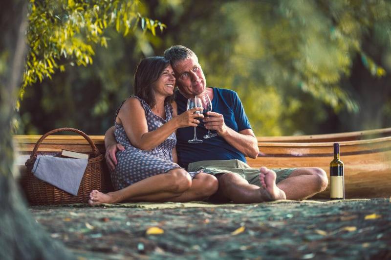 A couple sitting having a picnic together, enjoying glasses of wine.