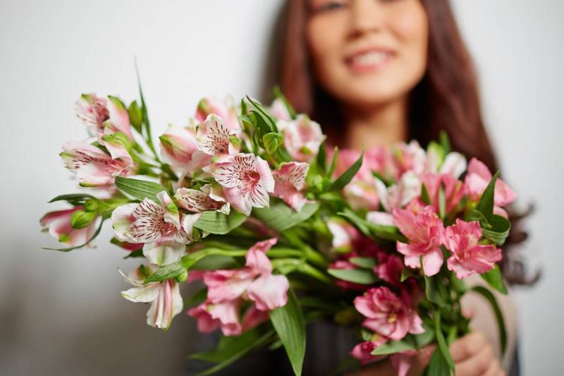 A woman holding a bouquet of pink and white flowers.