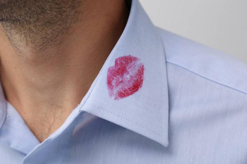 A man with a lipstick kiss mark on the collar of his shirt.