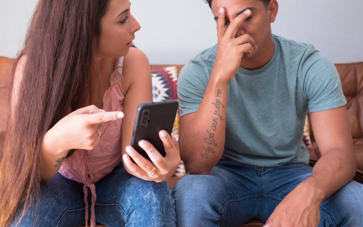 A woman confronting a man about what's on his phone.