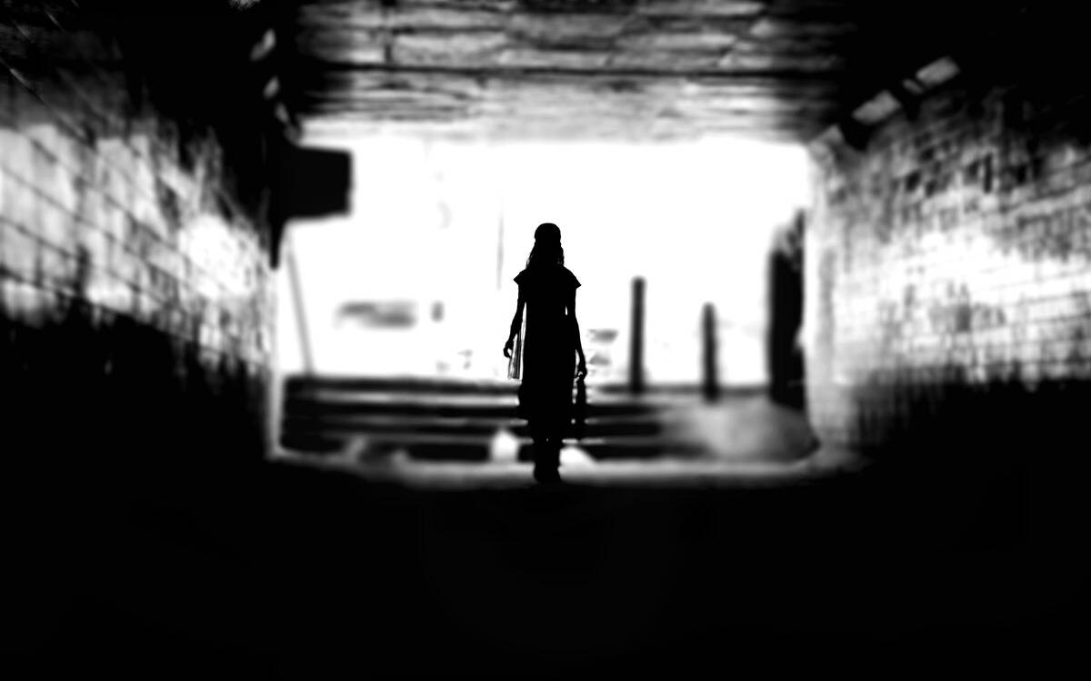 The silhouette of a woman walking down a dark alley.
