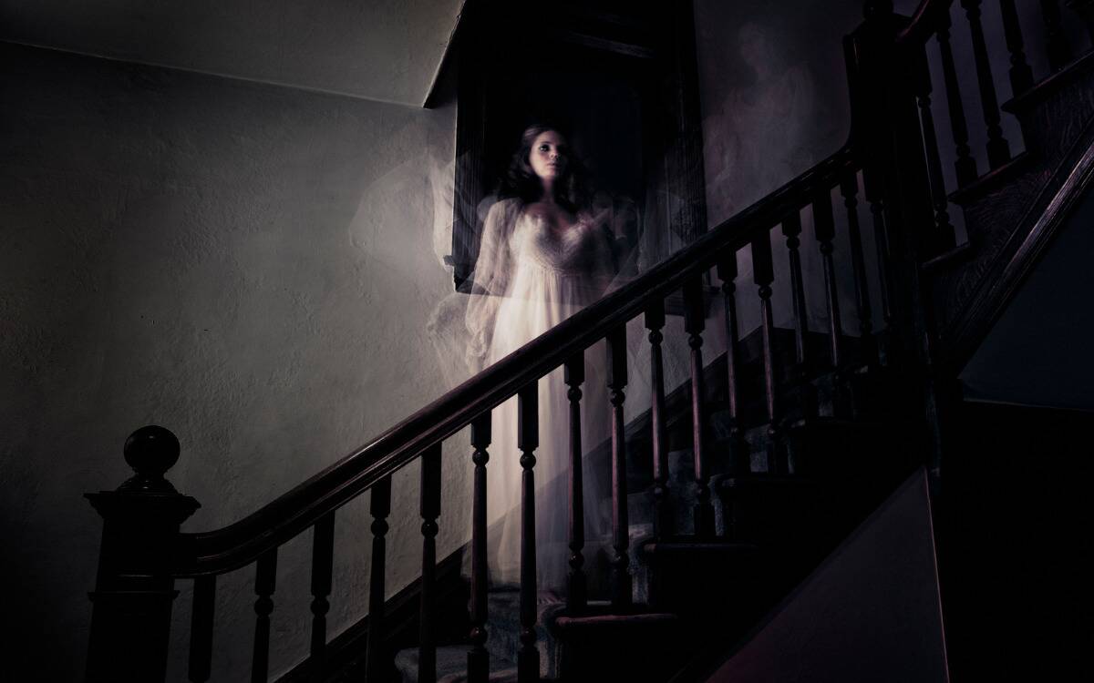 A ghostly woman standing on a staircase.