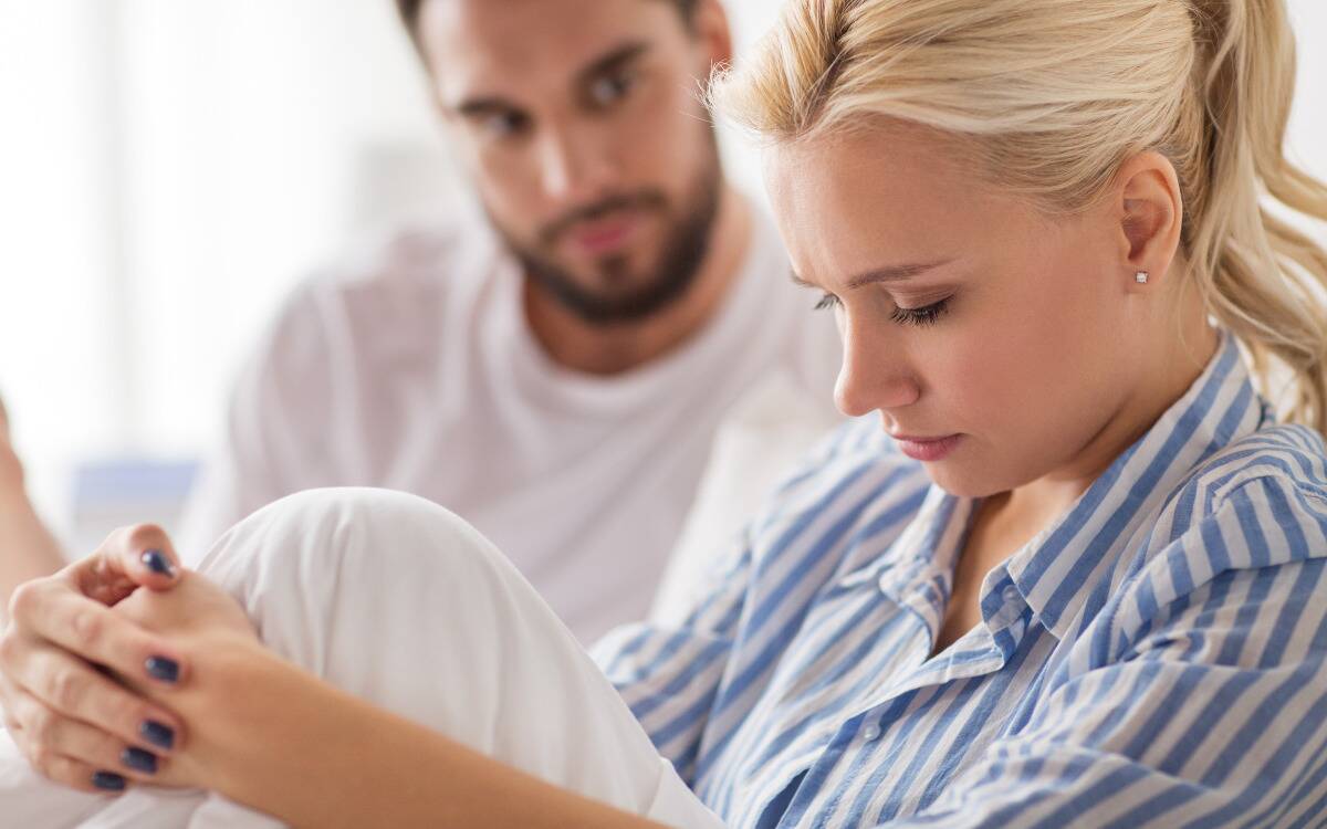 A woman looking sad while a man sits next to her.