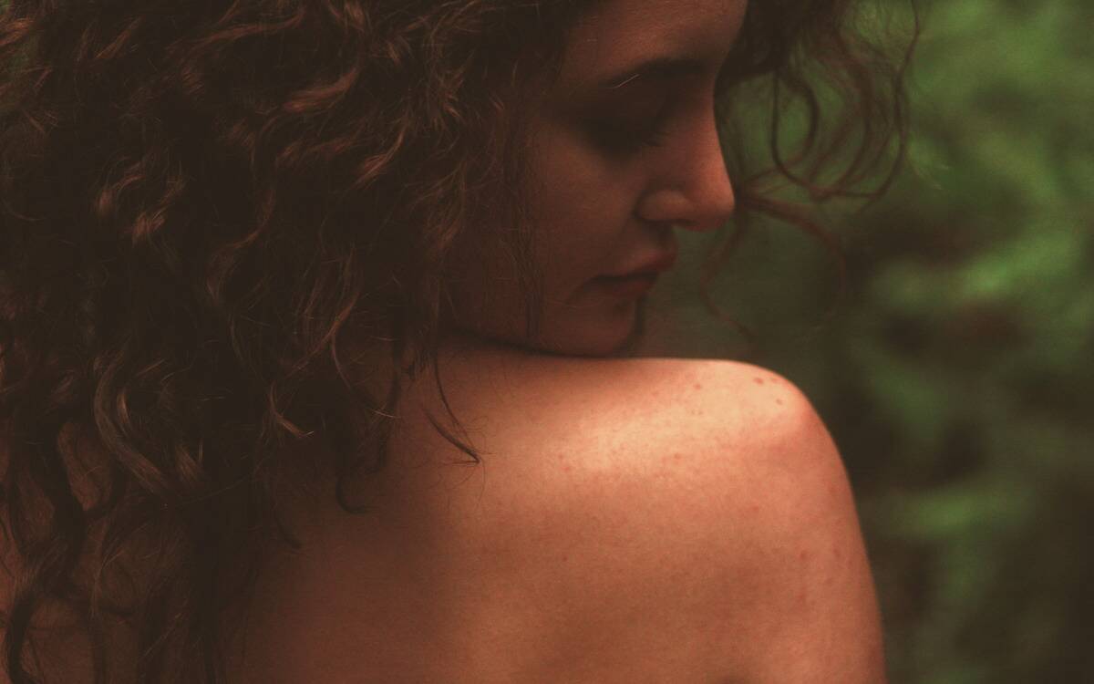 A woman looking at her own bare shoulder.