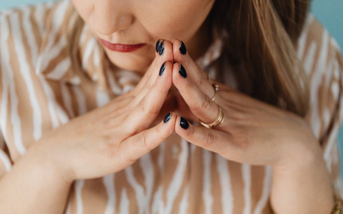 A woman with her fingertips pressed together in front of her face.