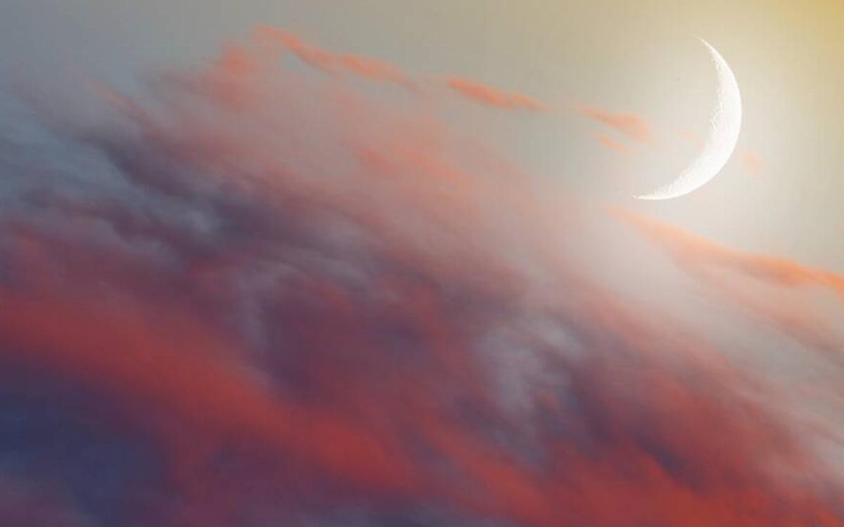 A new moon among colorful sunset clouds.