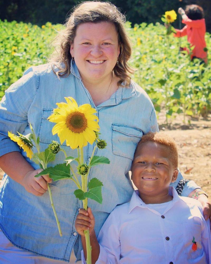 Archer with his mom, both holding sunflowers in a sunflower patch.