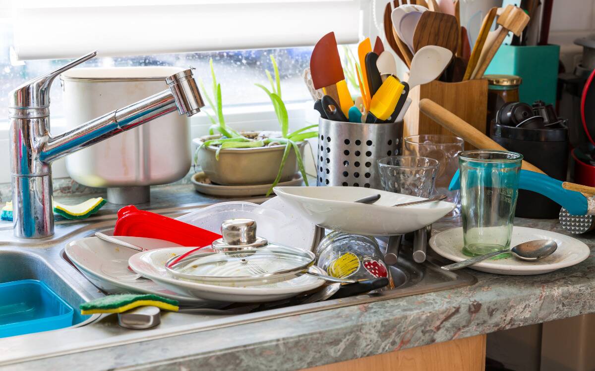 A kitchen sink and counter covered in dishes.