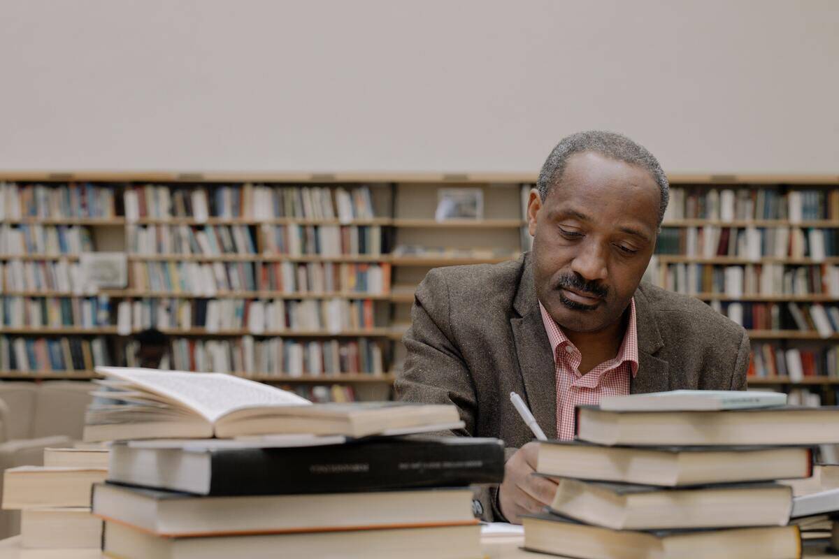 A man studying surrounded by stacks of books in a library.
