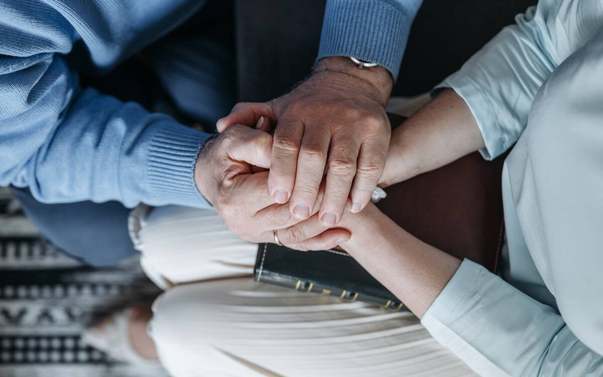 Two people holding hands, comforting one another.