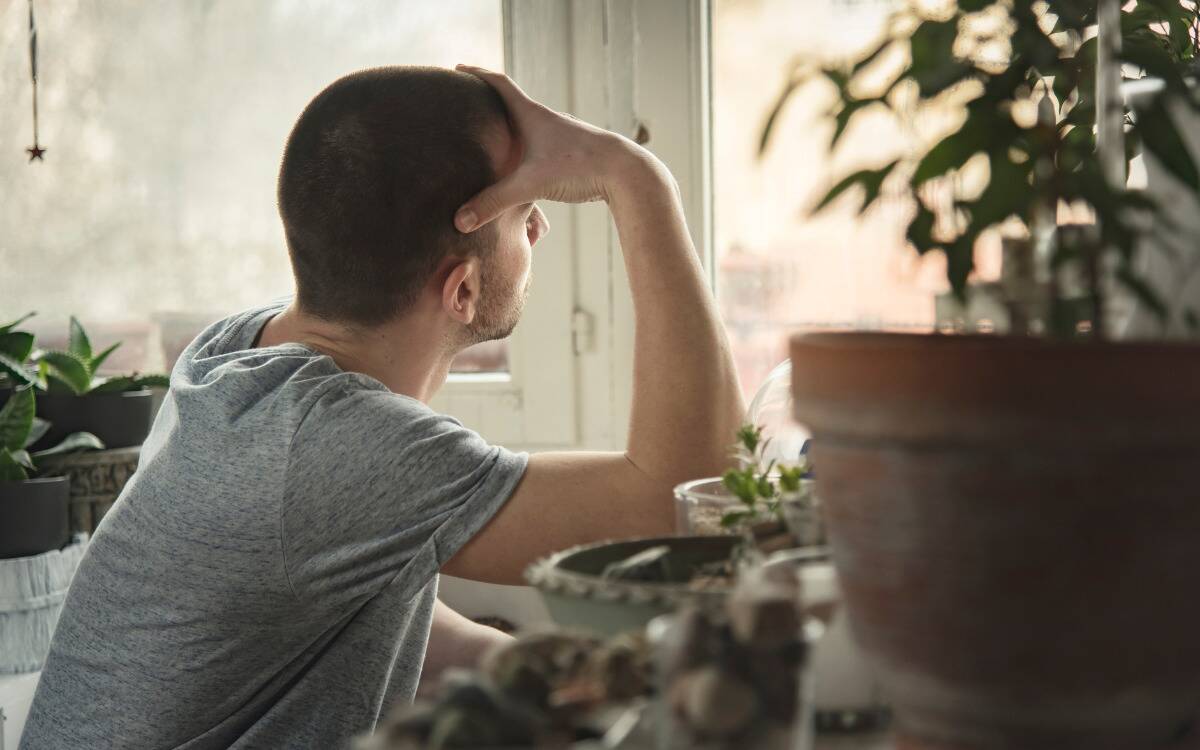 A man looking out his window forlornly.