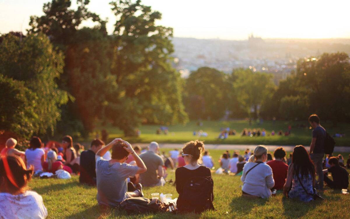 A community of people sitting on a park hill.