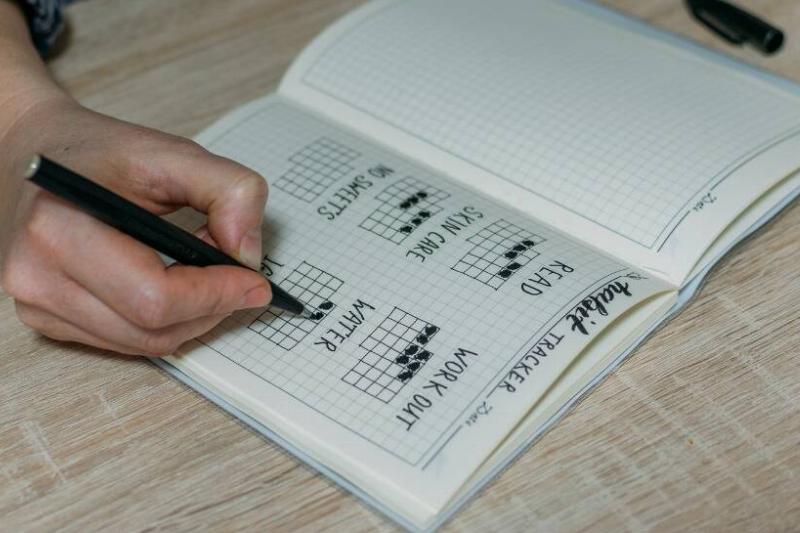 Someone filling out a custom habit tracker in a journal.