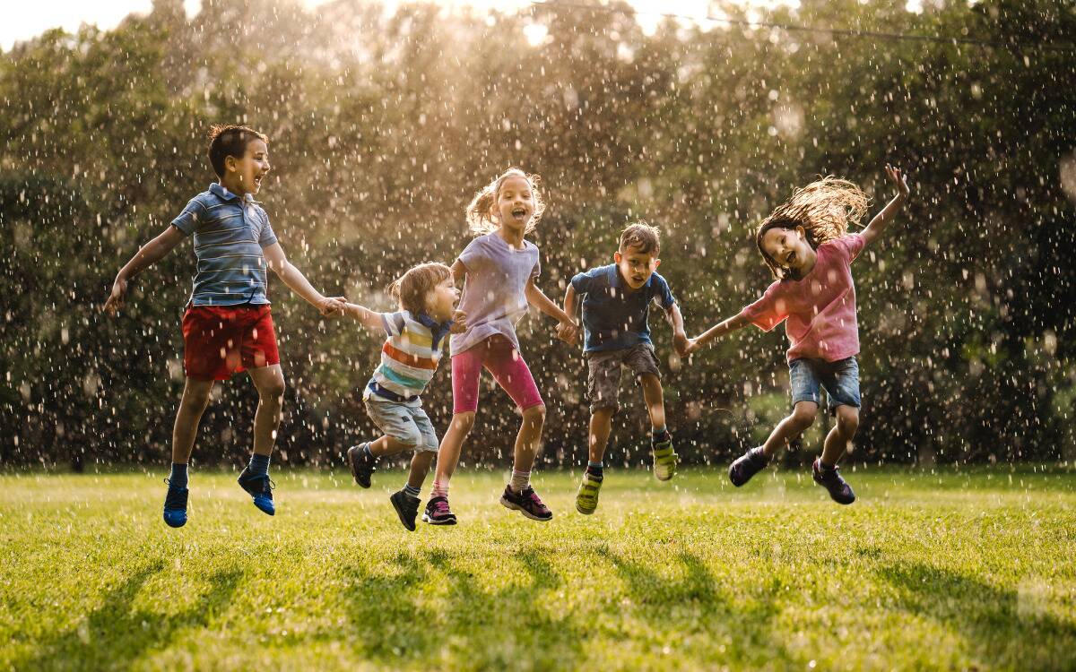 A group of kids playing in a sunshower.