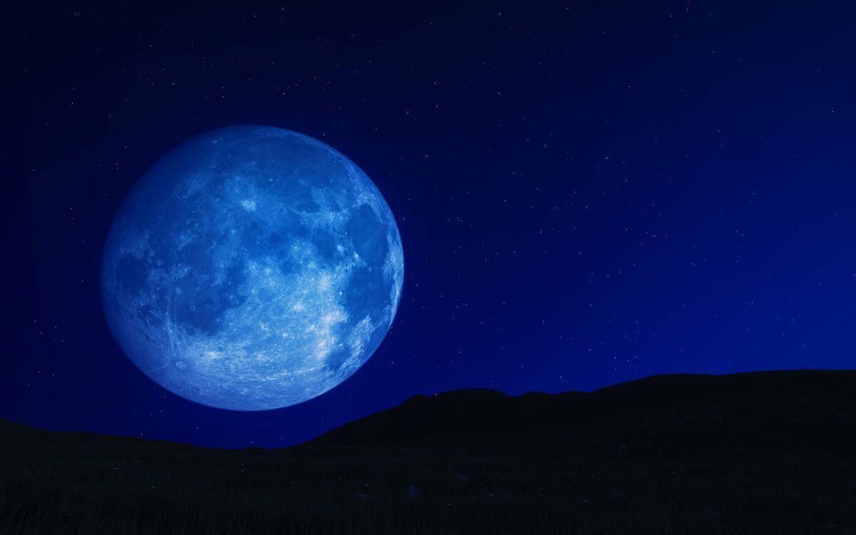 A large blue moon visible above a mountain range.