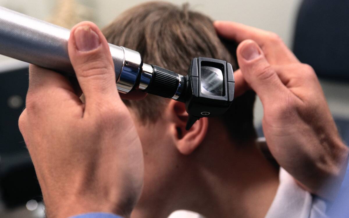 A doctor checking inside someone's ear with a scope.