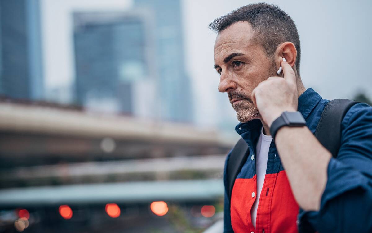 A man putting an AirPod in his ear.