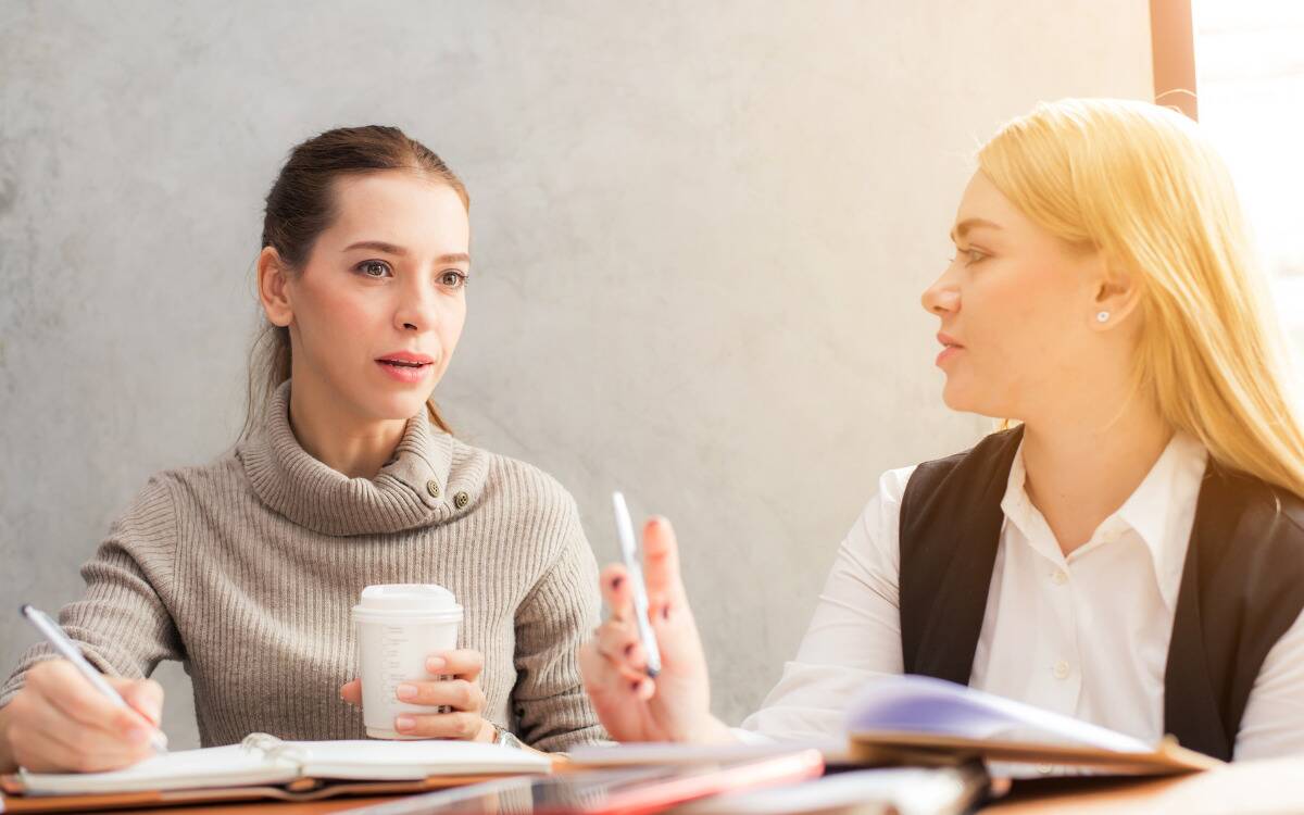 Two women talking as they work, one looking concerned.