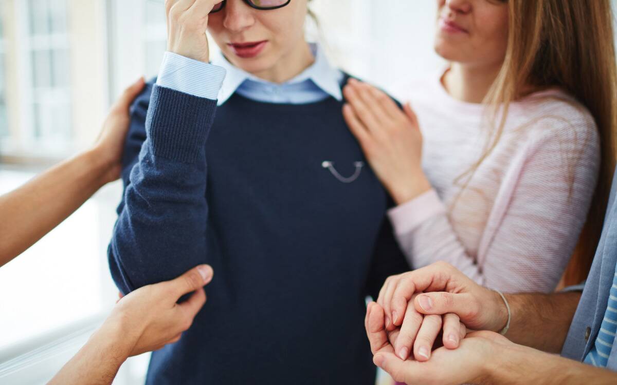 Multiple people consoling one woman who appears stressed.