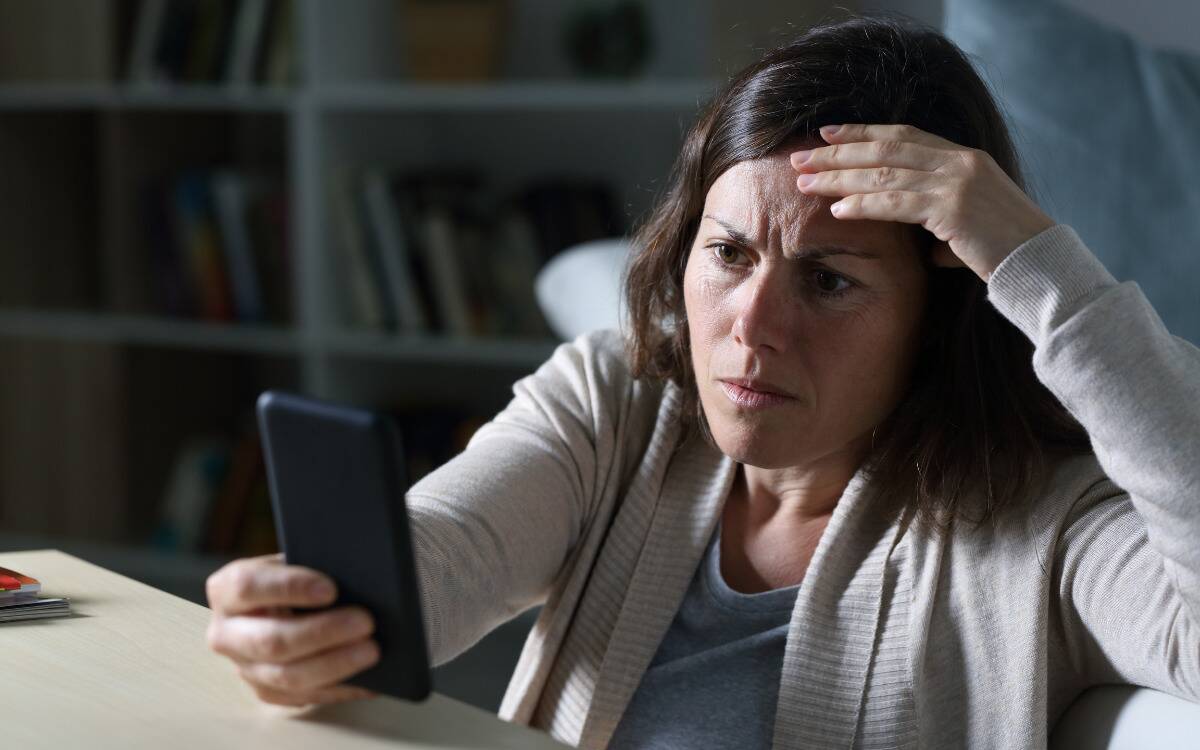 A woman looking distressed as she looks at her phone.