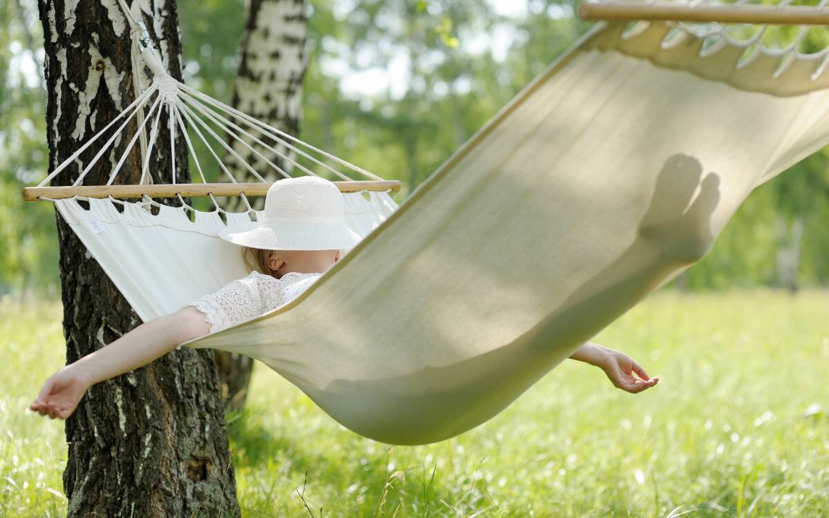 A woman relaxing in a hammock, a hat over her face.