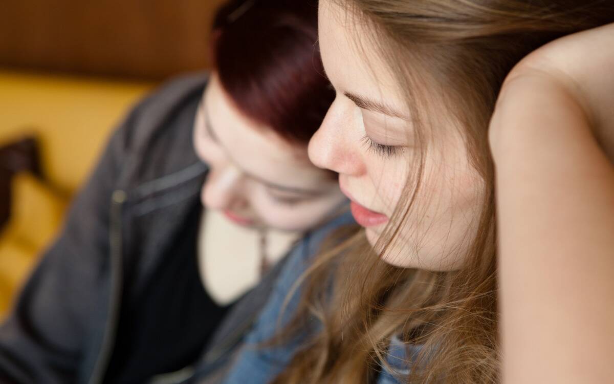 Two friends sitting together, one leaning on the other's shoulder.