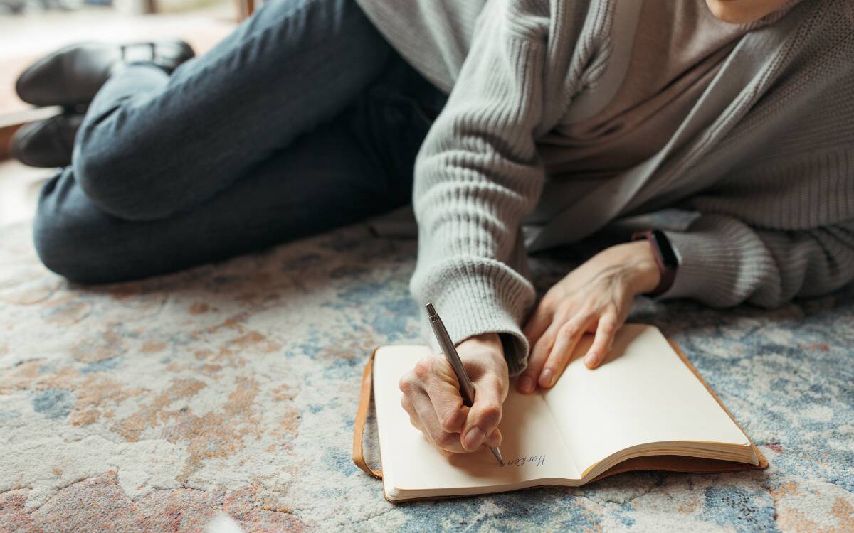 Someone laying on the ground to journal. 