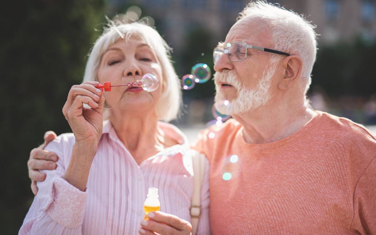 An elderly couple blowing bubbles together.