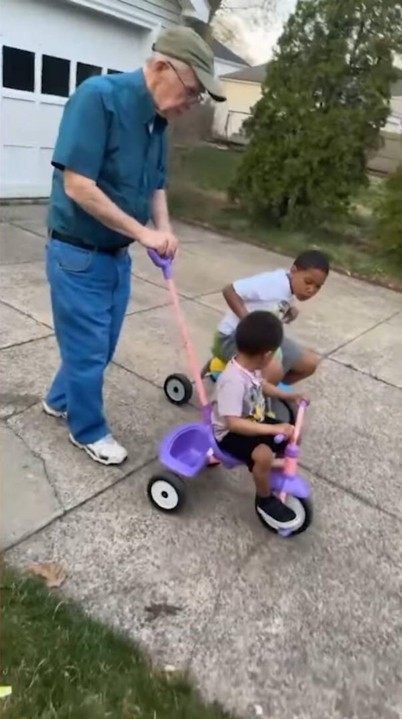 Paul pushing one of the young Carabello boys on his tricycle in the home's driveway.