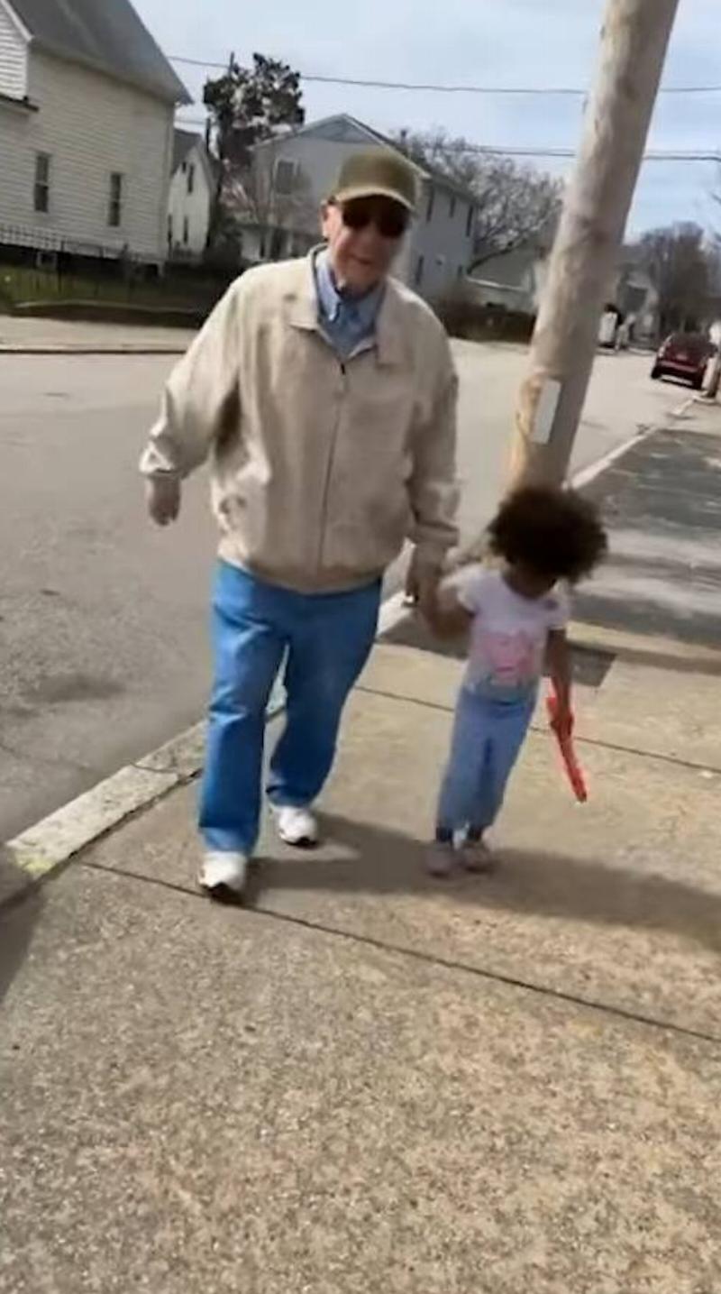 Paul holding hands with one of the young Carabello girls as they walk down the street.