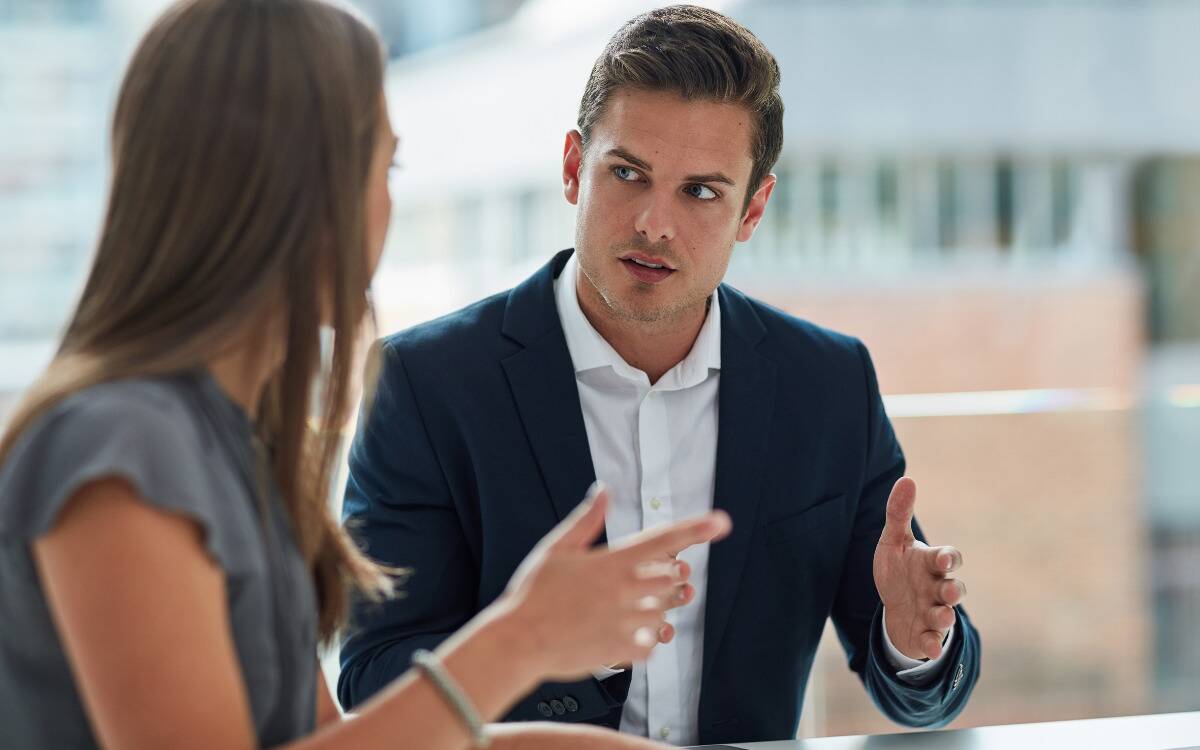 A man and a woman having a conversation, the man looking a bit confused, surprised.