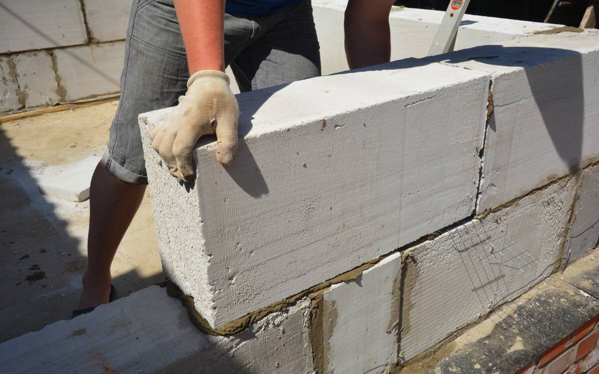 Someone laying a large brick in a wall.
