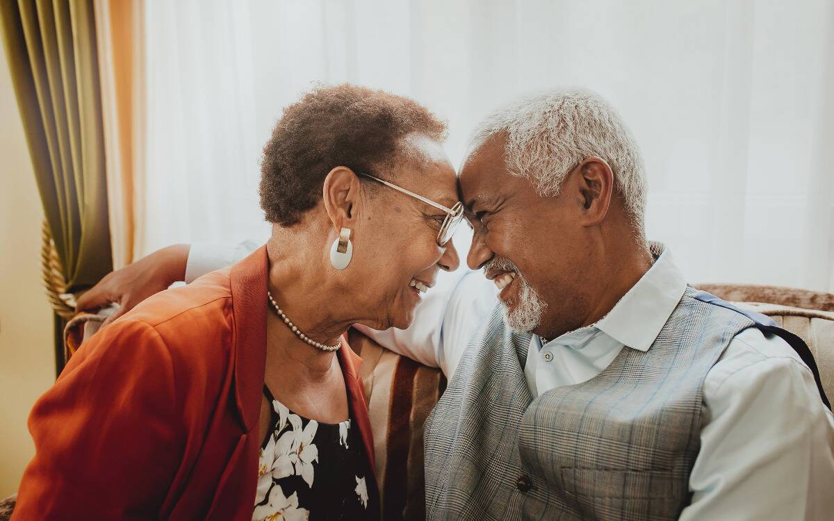 An older couple smiling with their foreheads pressed togheter.