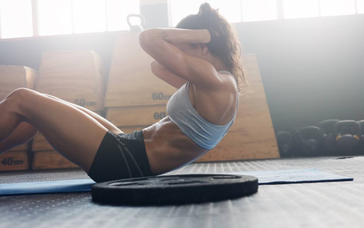 A woman doing a sit up on a gym floor.
