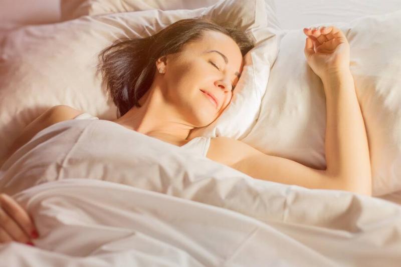 A woman happily asleep in bed.