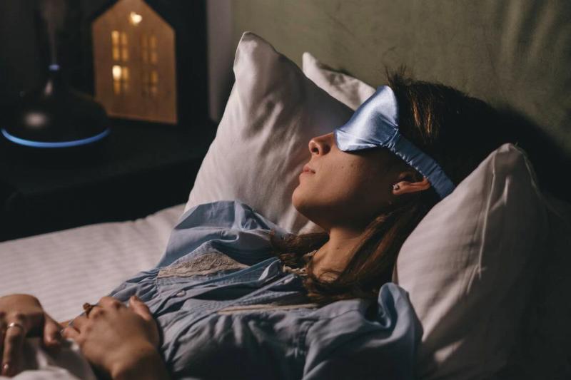 A woman asleep in bed with an eye mask on.