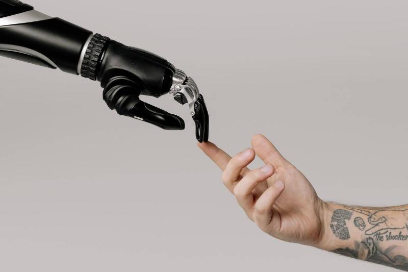 A robot and a human hand reaching out to each other to touch fingertips.