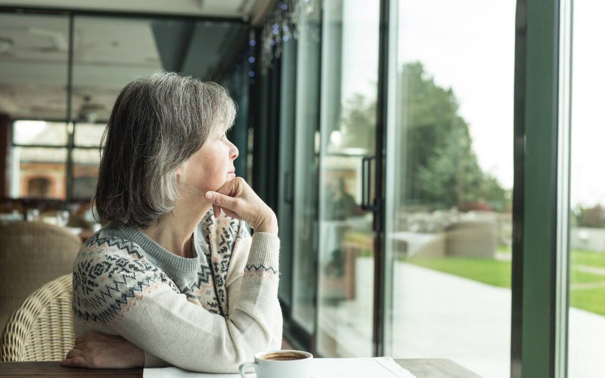 A woman looking wistfully out a window at a cafe.