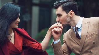 A man kissing a woman's hand romantically.