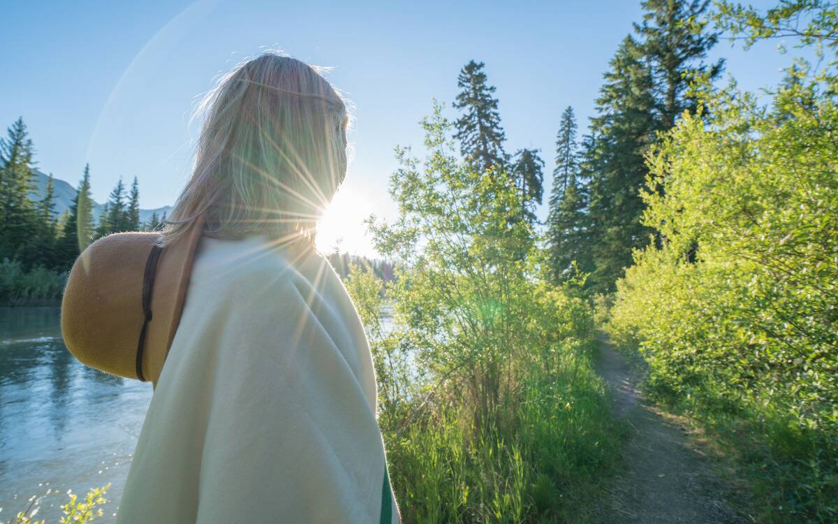 A woman walking in nature looking toward the sunrise.
