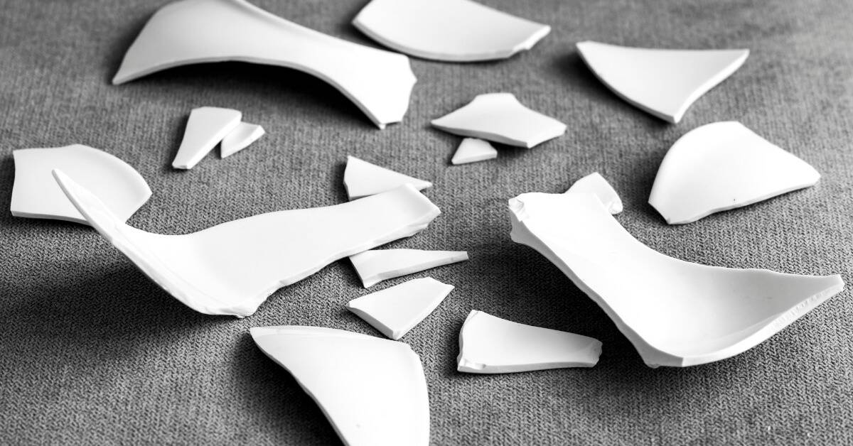 Broken pieces of unidentified ceramic on a carpet floor.