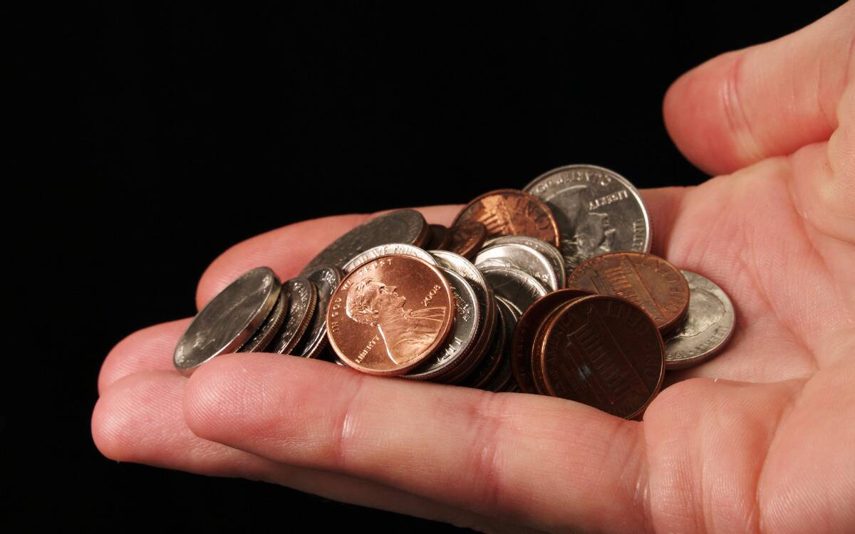 Someone's hand holding a small handful of various coins.