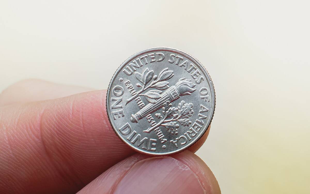 A closeup of a dime on someone's finger.