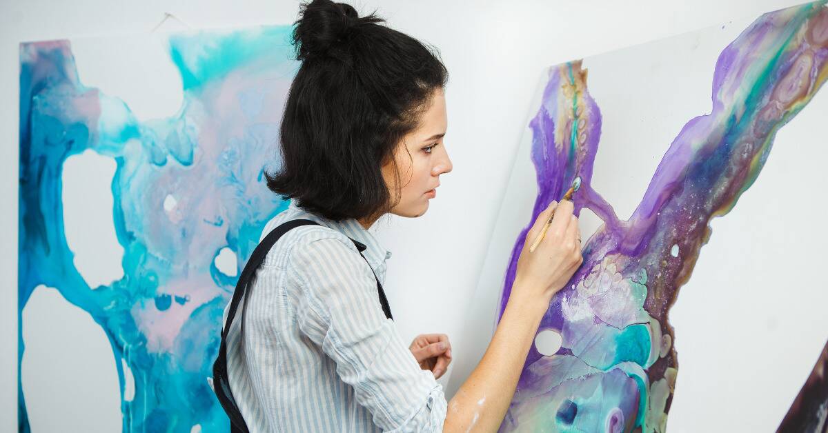 A woman painting on an already-colorful canvas.