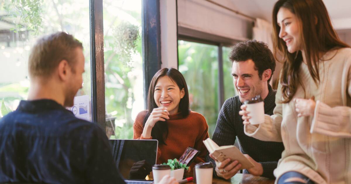 A group of friends at a cafe, smiling as they chat.
