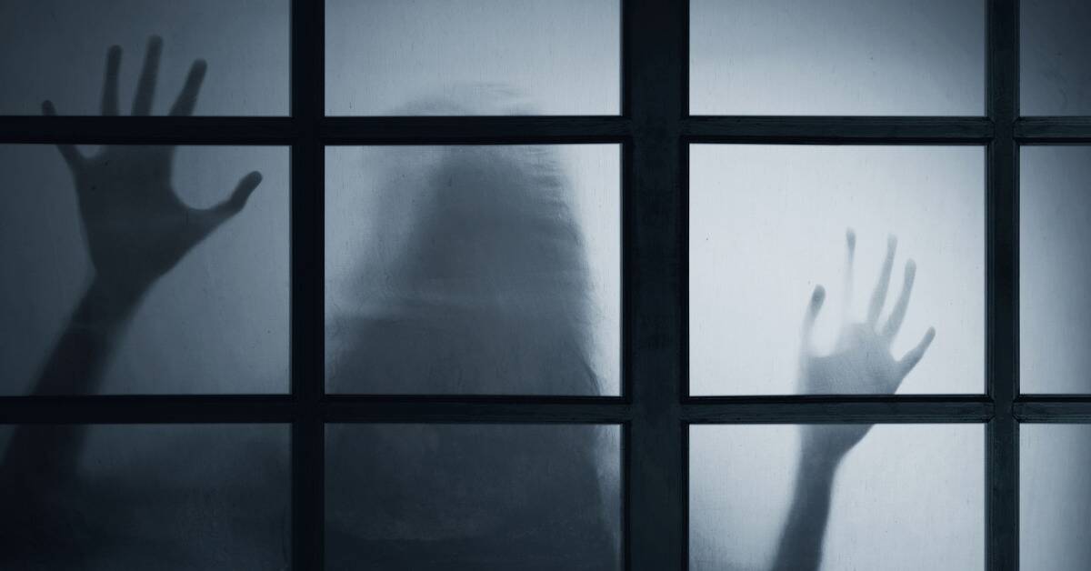 A ghostly figure visible through a frosted glass door, its hands against the glass.