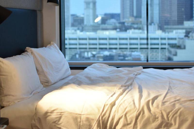 An empty bed next to a large window.