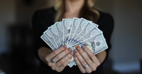 A woman fanning out $100 bills in front of her.