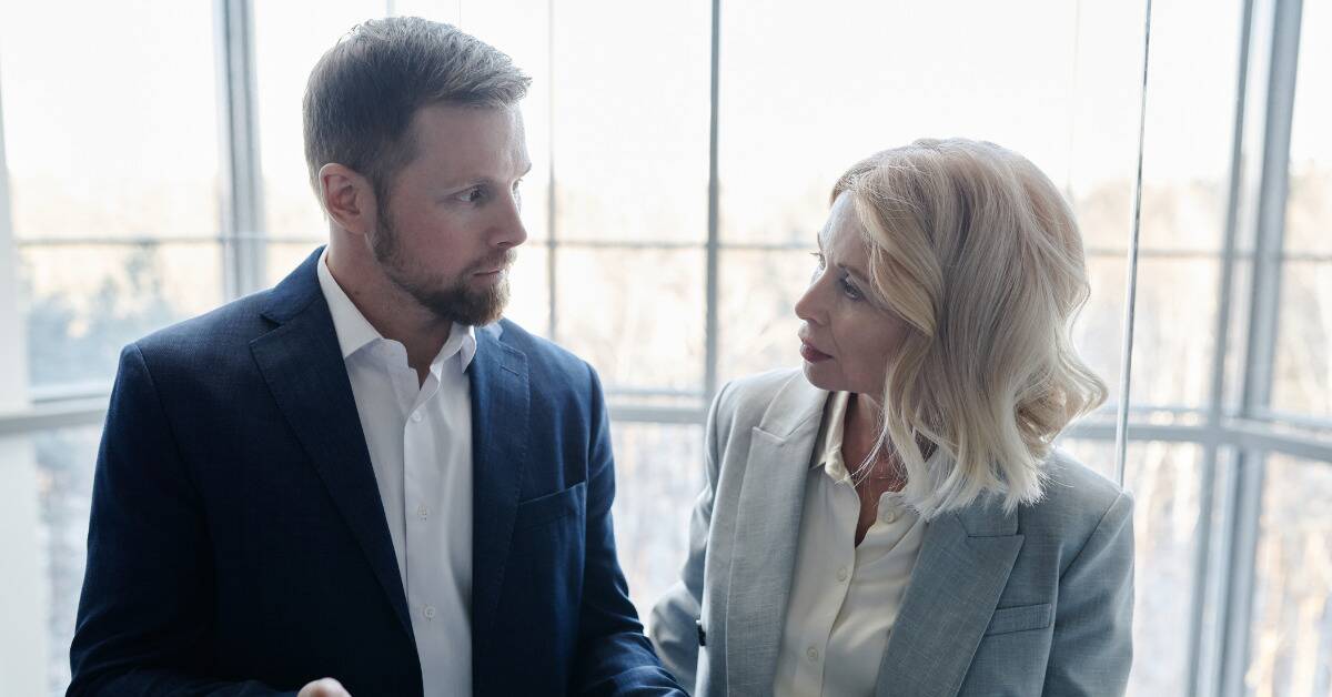 A man and a woman at work looking at one another, the man appearing nervous while the woman looks incredulous.